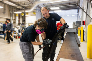 The instructor showing a student how to sand car parts during class at Crockett high school (ACC South Austin campus.)