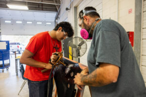 A student working on car parts with an instructor during class at Crockett high school (ACC South Austin campus.)