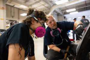 A student working on car parts with an instructor during class at Crockett high school (ACC South Austin campus.)