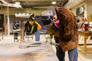 A student drilling car parts in class.