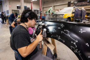 A student hammering car parts in class.