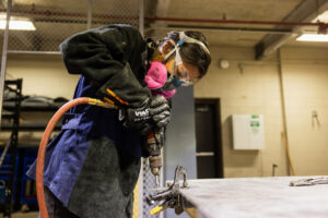 A student drilling car parts in class.